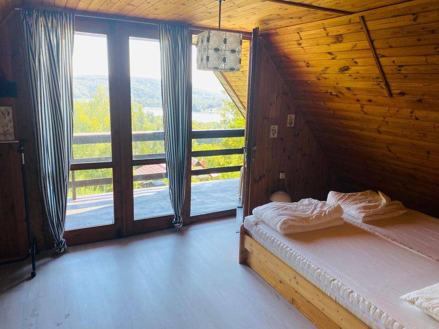 Prosklené dveře z ložnice na balkon, za nimi zeleň a voda